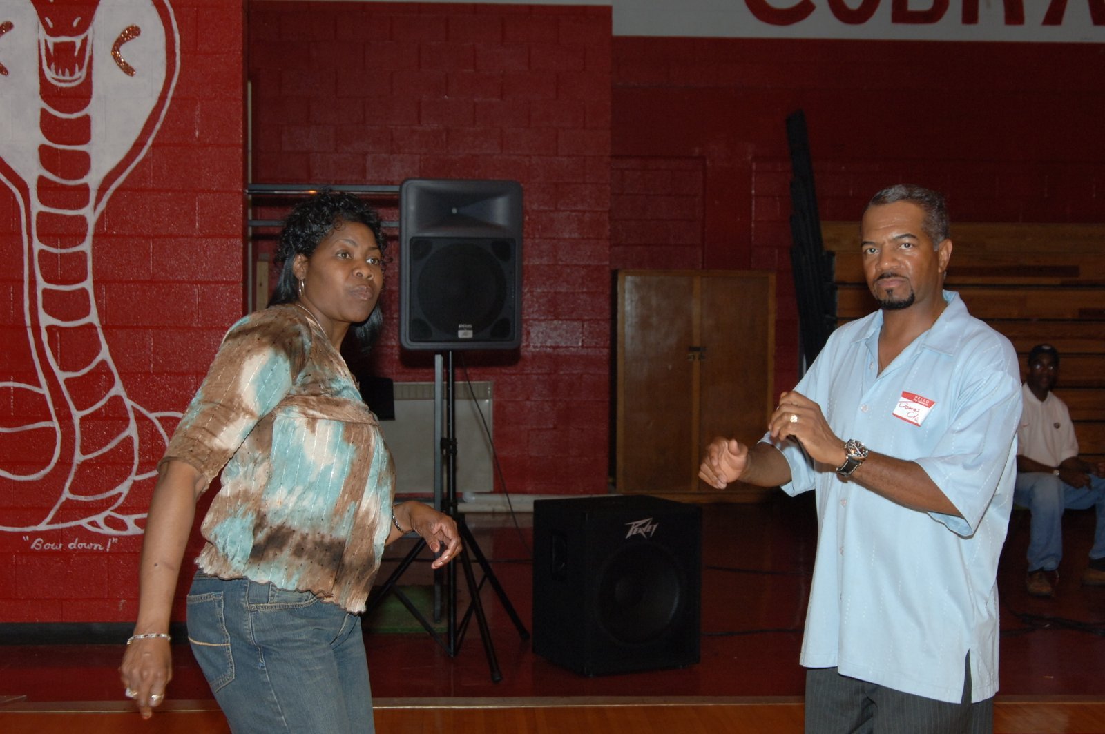 Alumni woman and man at school gymnasium event with microphone