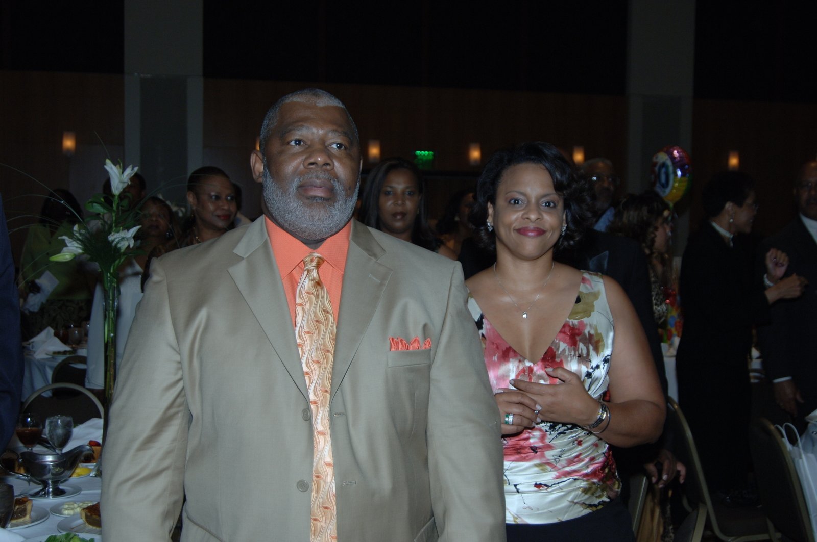 Alumni man in beige suit with woman at formal event