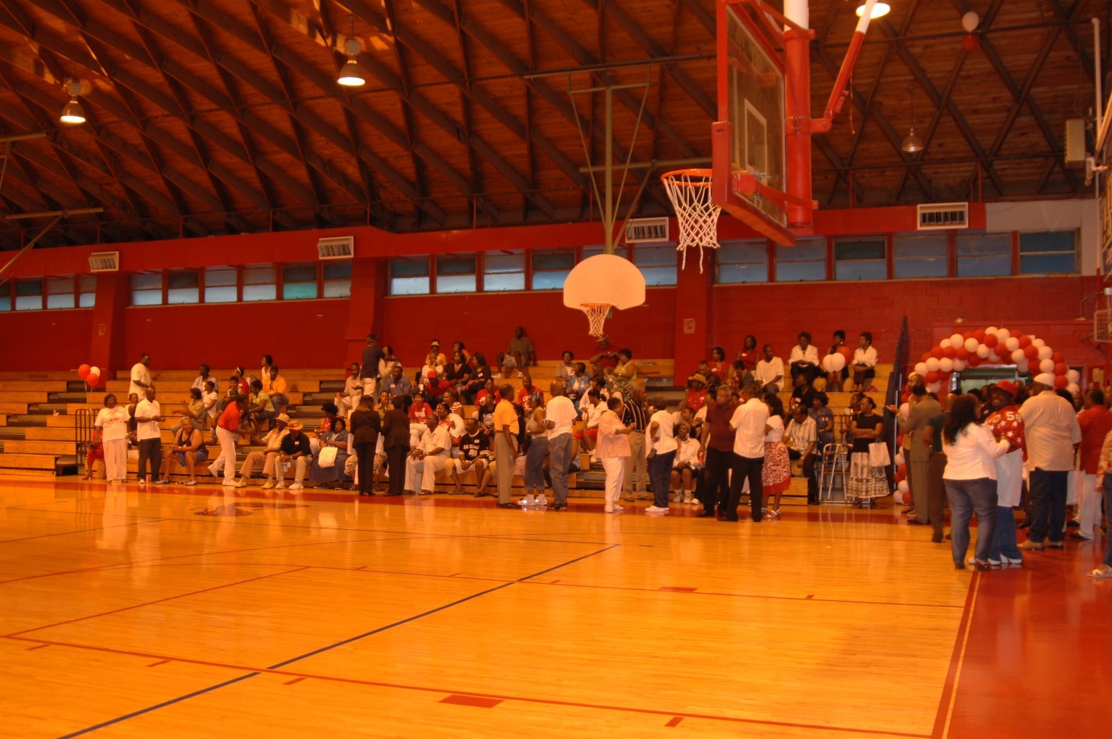 Alumni gathered in school gymnasium with red and white balloons