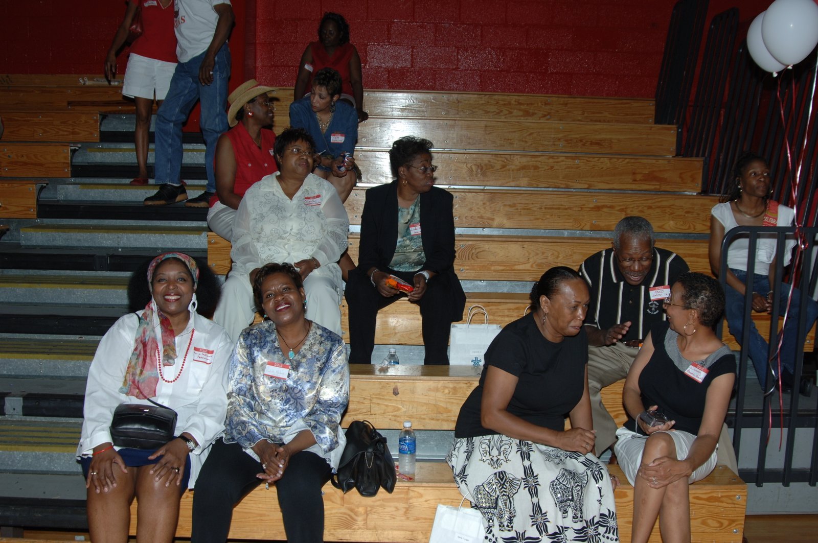 Alumni seated on bleachers at school event with red and white decor