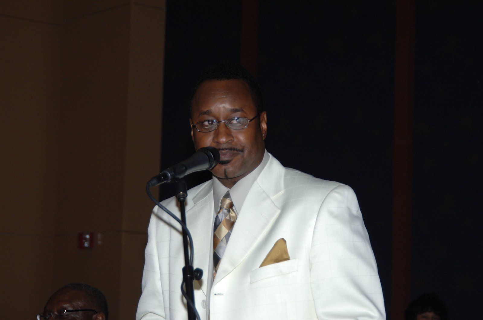 Alumni speaker at microphone at formal event