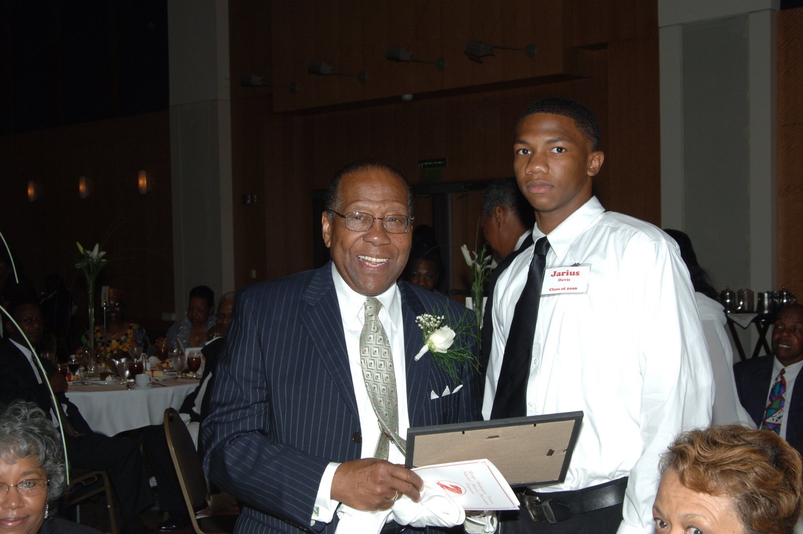 Alumni man and young man at formal event with certificate of appreciation
