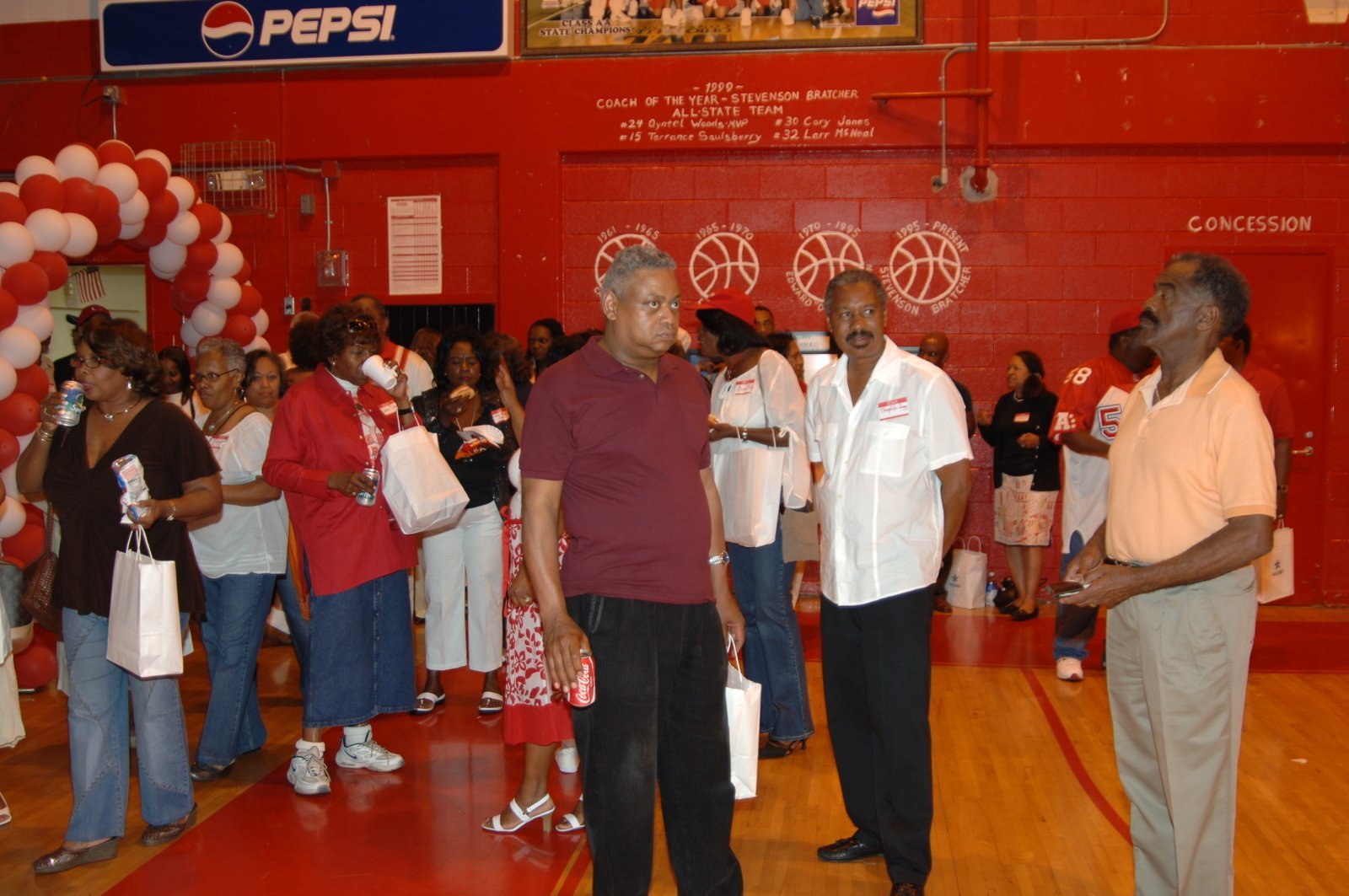 Alumni at school gymnasium event with Pepsi sign and red and white decor