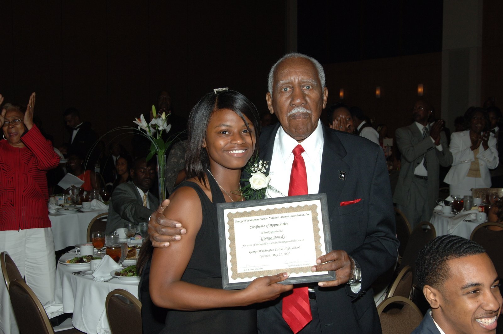 Alumni man and woman at formal event with certificate of appreciation