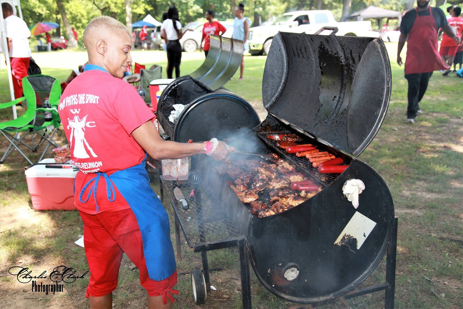 Alumni at outdoor park event cooking on grill