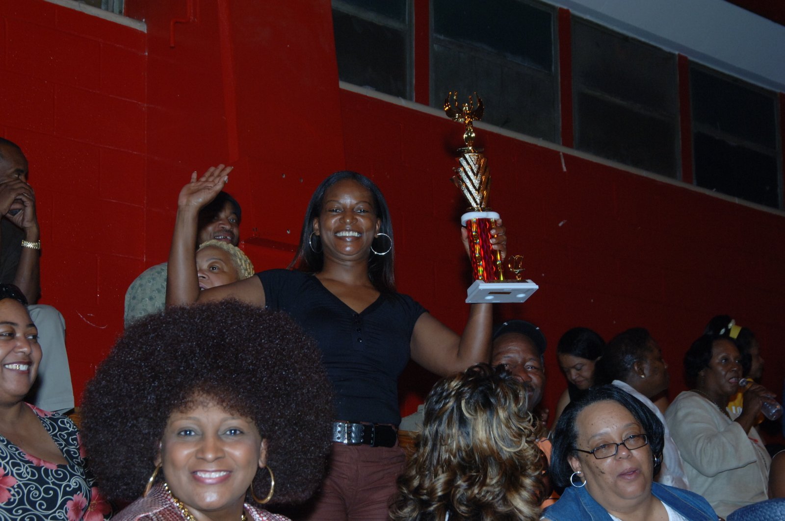 Alumni woman holding trophy at school gymnasium event