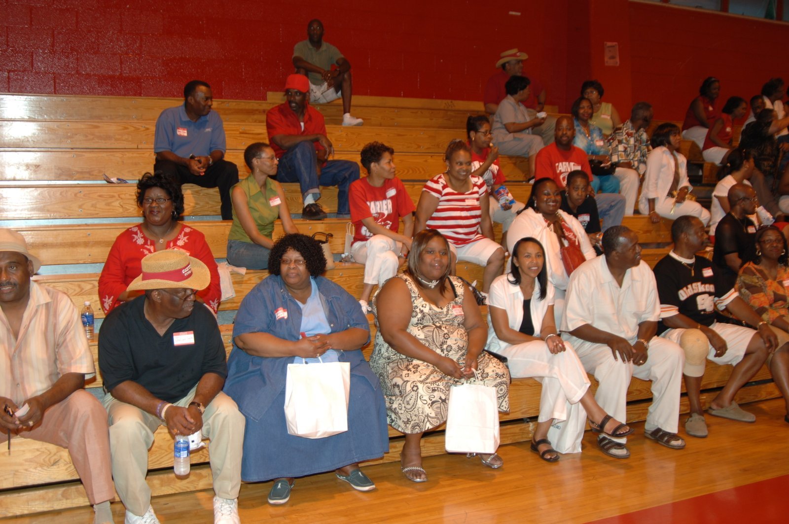 Alumni seated on bleachers at school gymnasium event