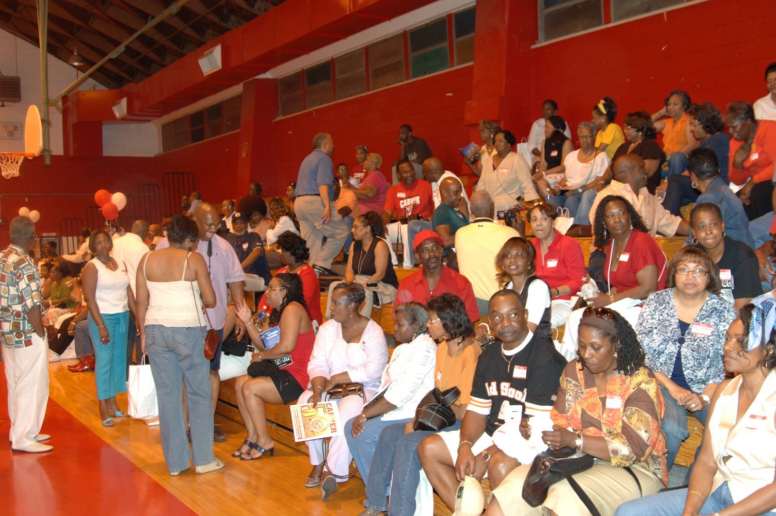 Large group of alumni gathering and talking casually at a gymnasium event