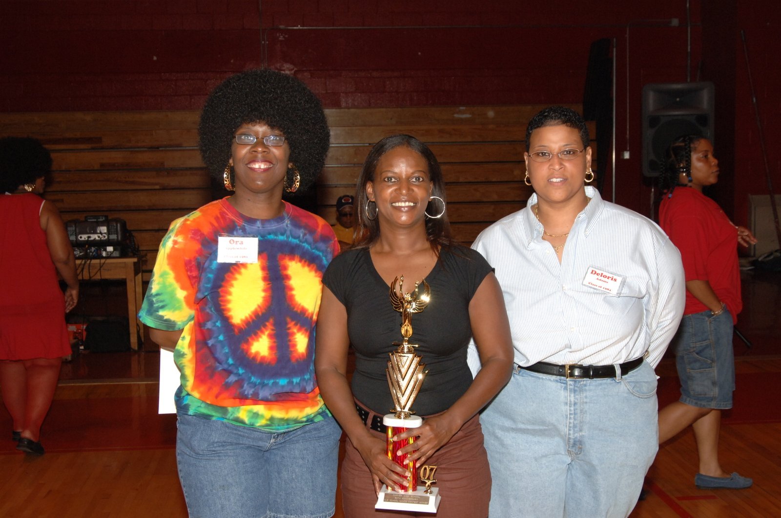 Alumni women at school gymnasium event with trophy