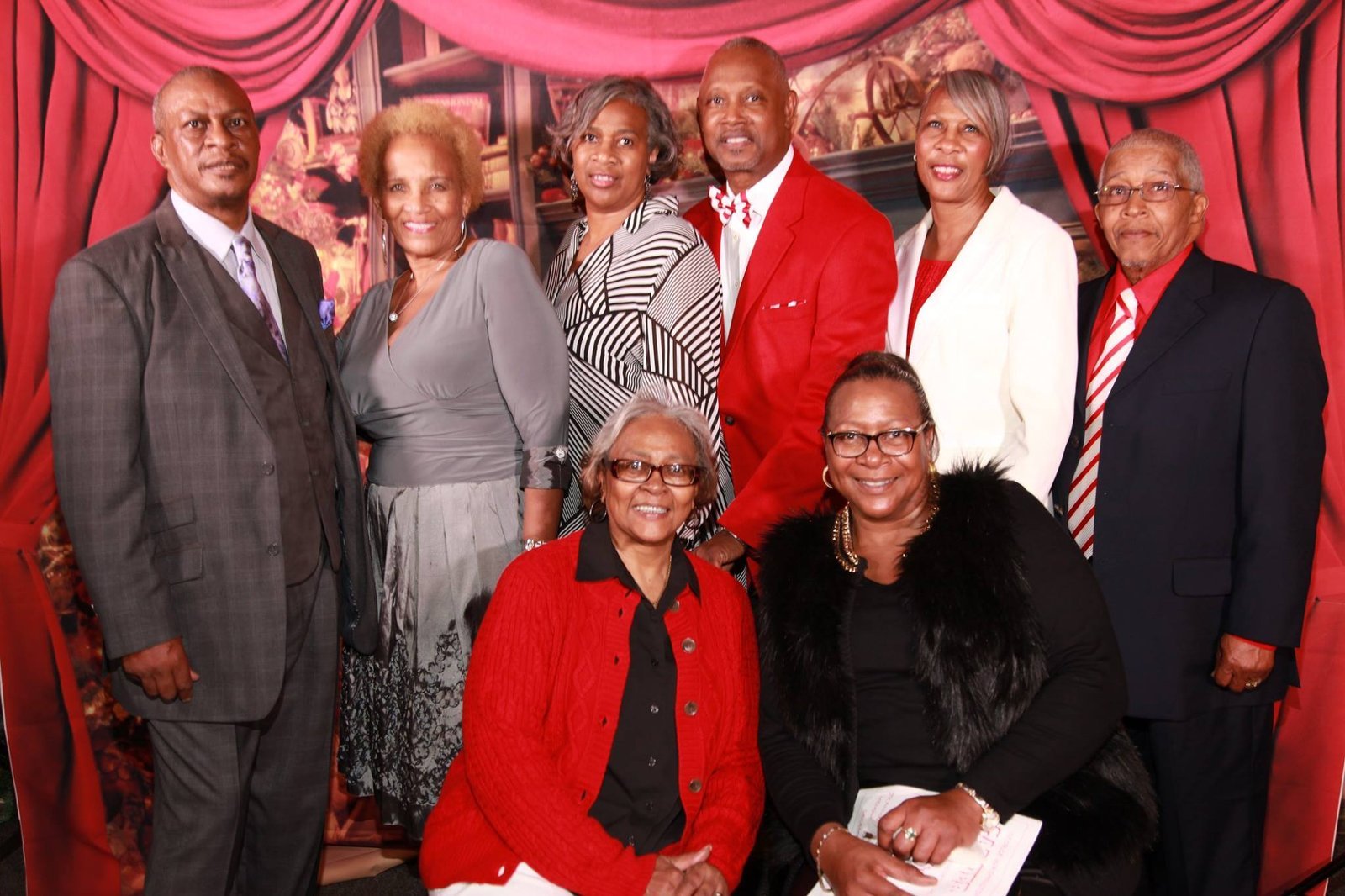 Alumni group photo at formal event with red backdrop