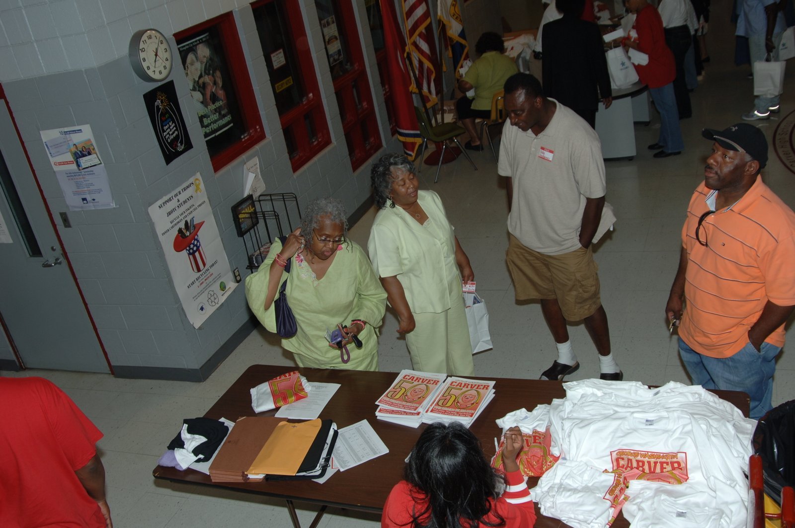 Alumni gathering at school event with merchandise table