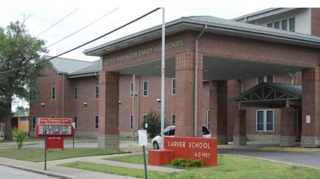 Modern brick Carver High School building with red sign 'CARVER SCHOOL AD 1957'
