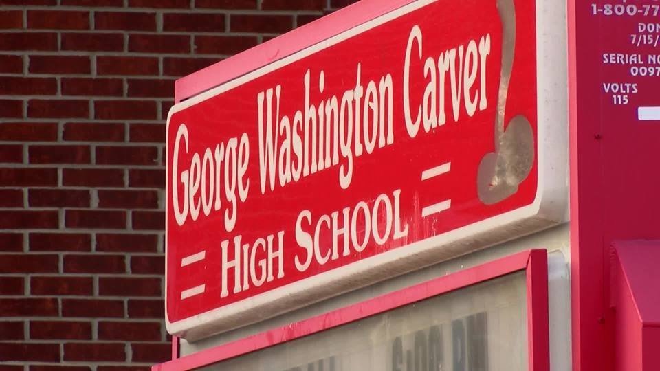 Close-up of red 'George Washington Carver High School' sign on brick wall