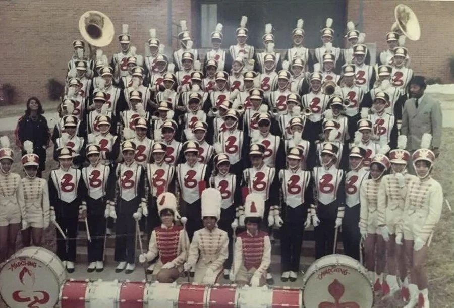 Vintage marching band group photo in white uniforms with red accents